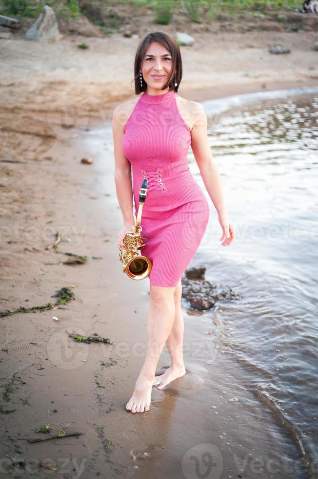 Woman playing the saxophone at sunset. photo