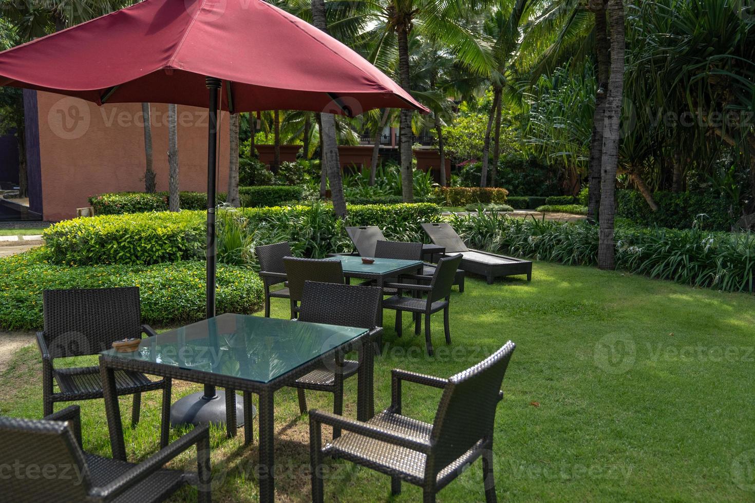 the basketry chair, table and red umbrella set in the garden, in the relax area. photo