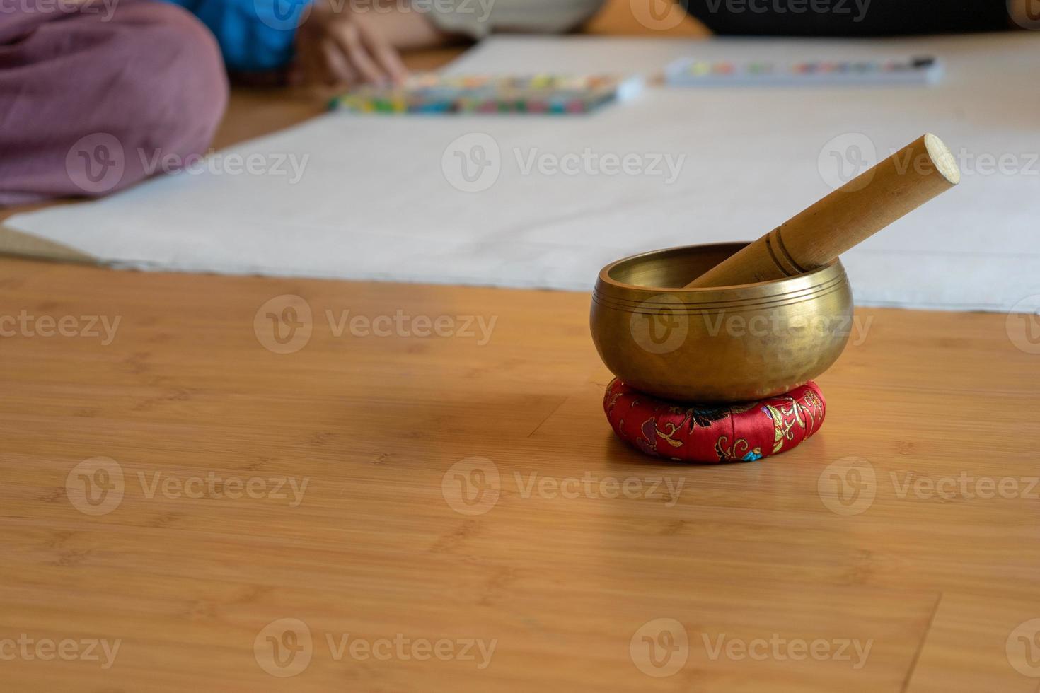 cuenco de latón sobre la base de tela yacía en el suelo de madera. es el truco vintage asiático para hacer sonar una señal y un sonido para notar el seminario y el taller para llamar la atención del orador. foto