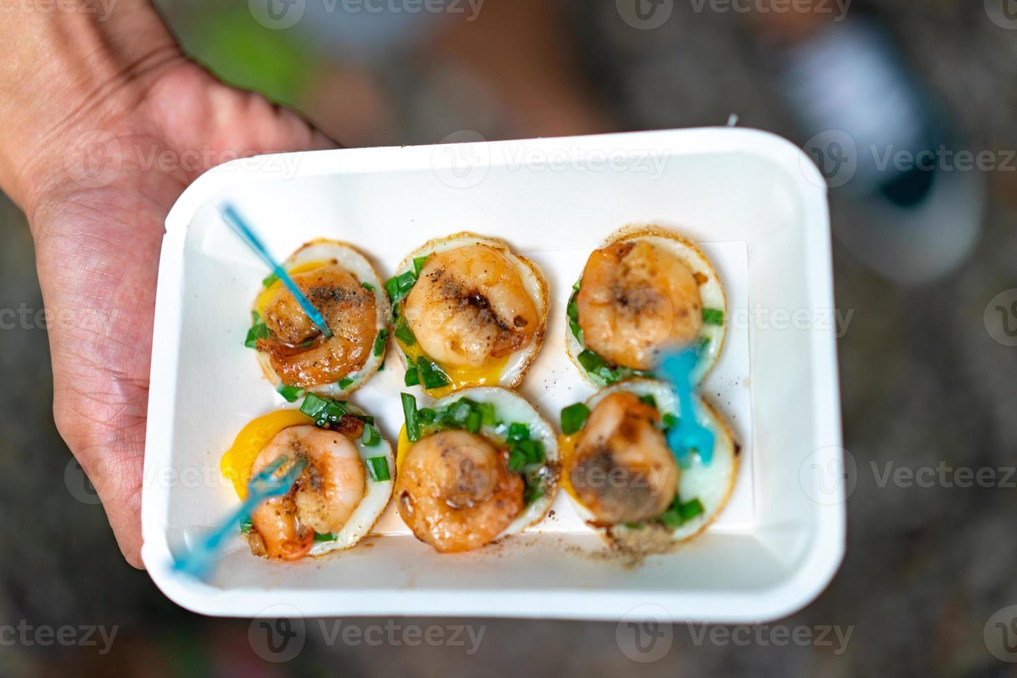 fried Quail eggs top up with boiled and fried shrimp, in the paper plate and plastic fork. photo