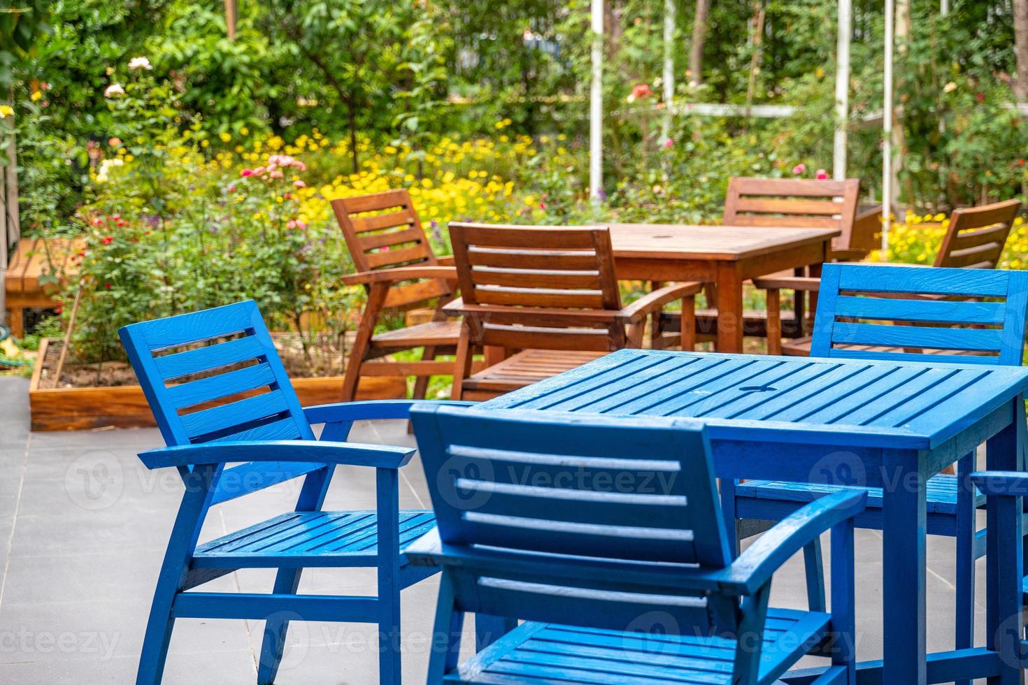 wood blue and brown deck, chair and table set in the garden with colorful flower field background. photo