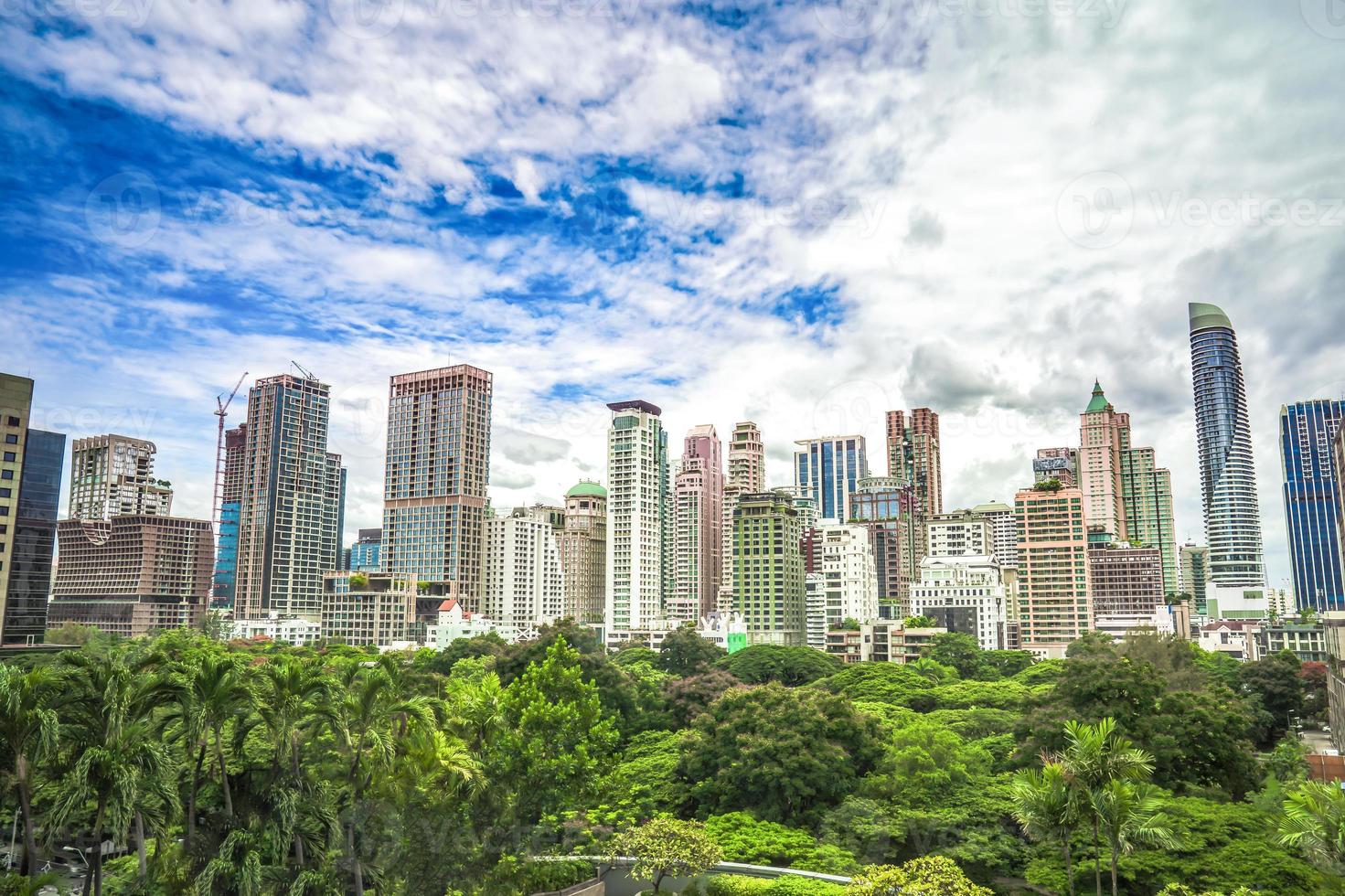 Green area in front of the middle of Bangkok metropolis with high building all around in the open sky. photo