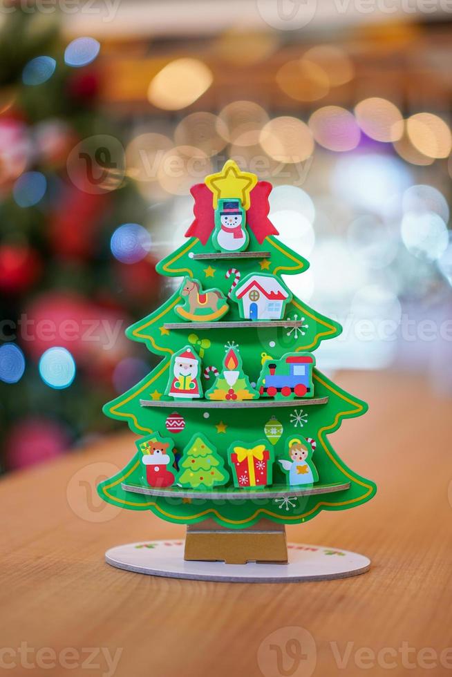 Christmas tree paper craft decoration on the wood table with blur big Christmas tree behide. photo