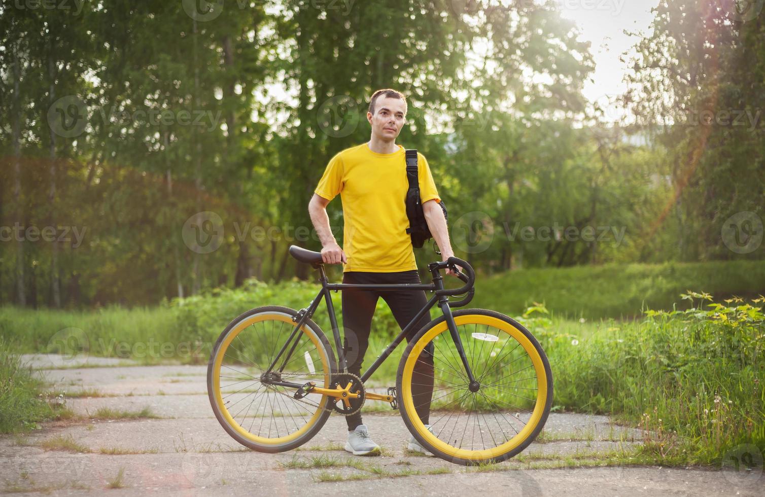 A young Man stopped to rest With his Bicycle in a public Park. photo