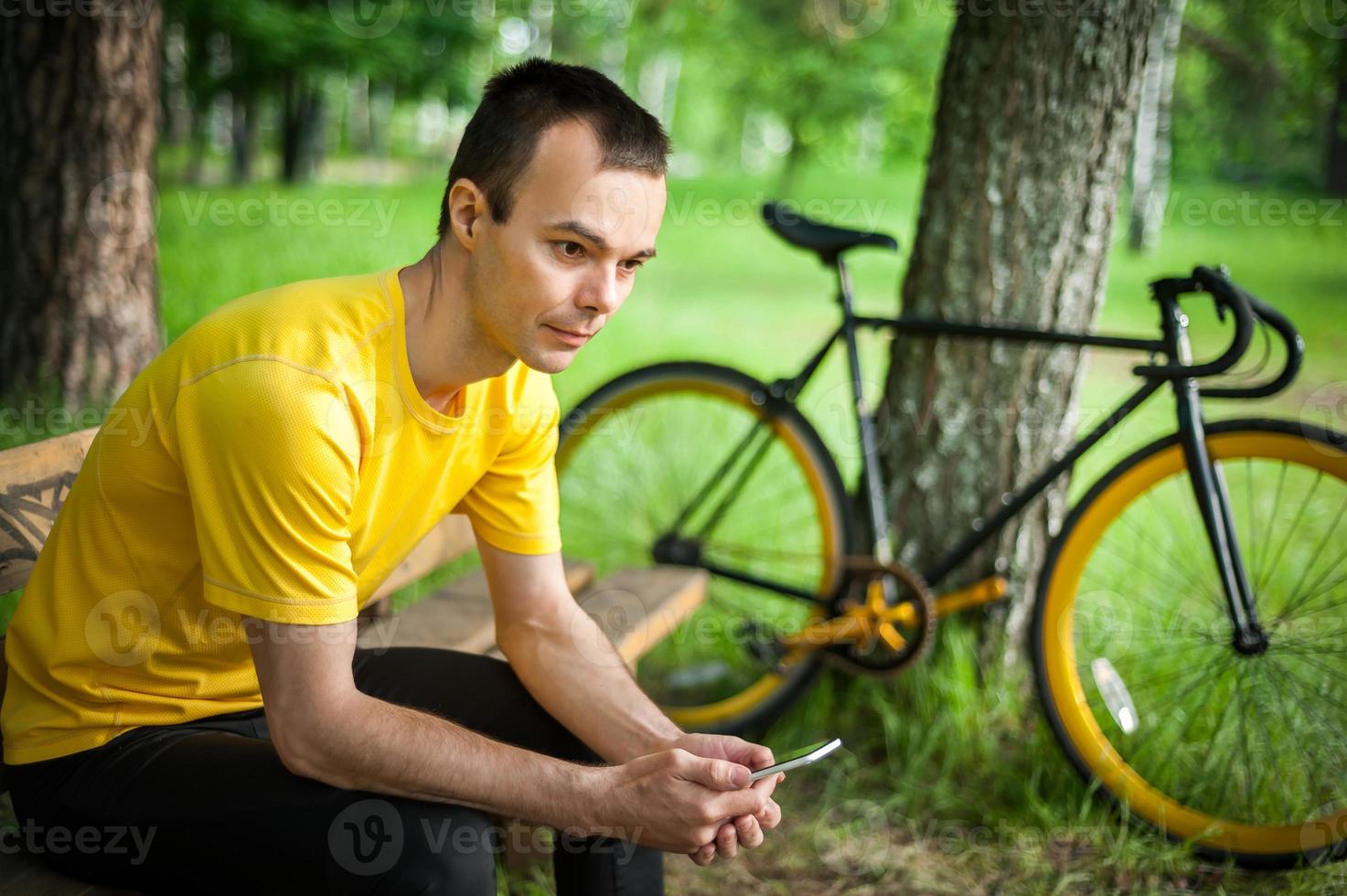 A young man sitting on a bench in a public Park communicates via mobile communication. photo