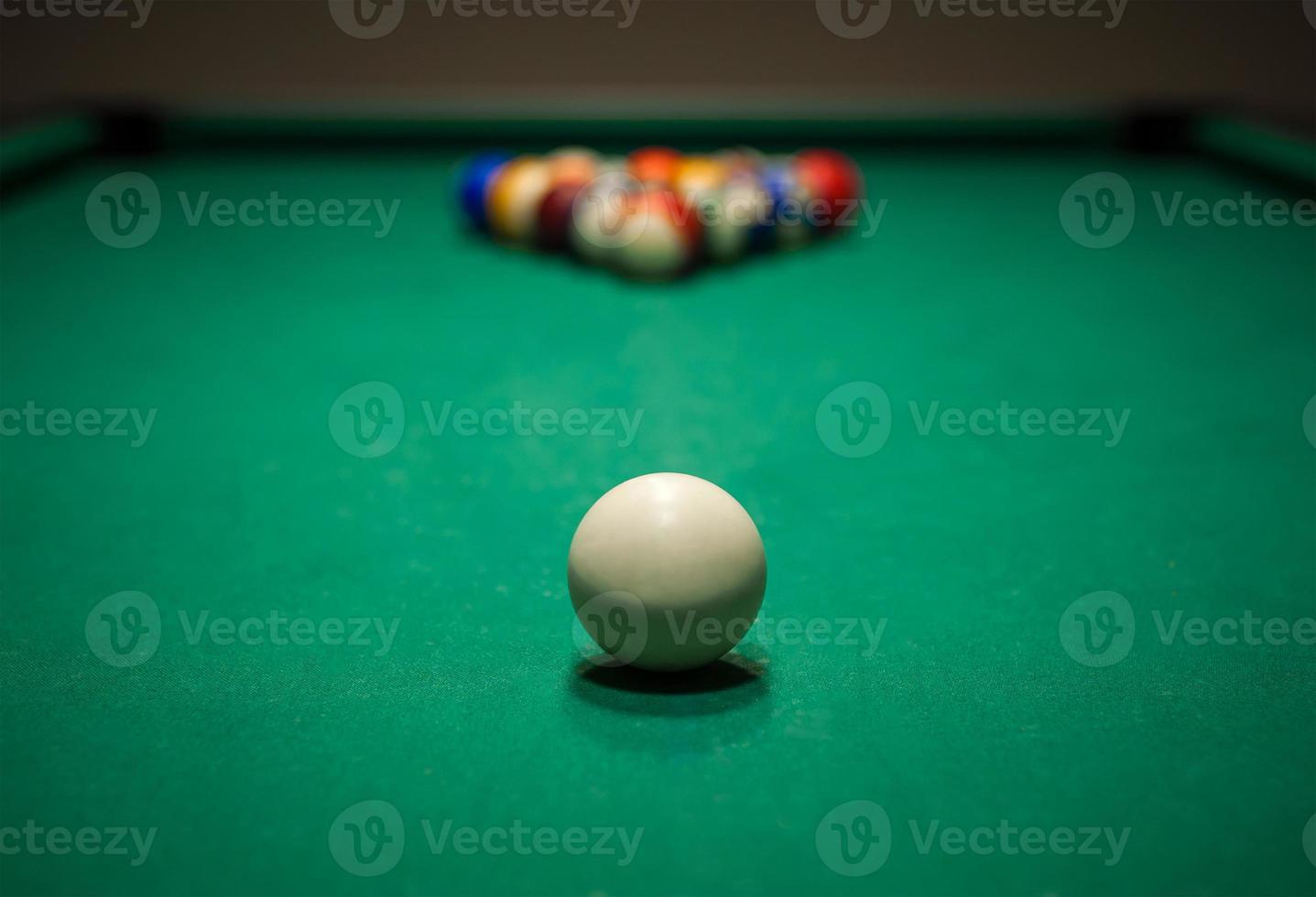 Sport billiard balls set arranged in shape of triangle on green billiard table in pub photo