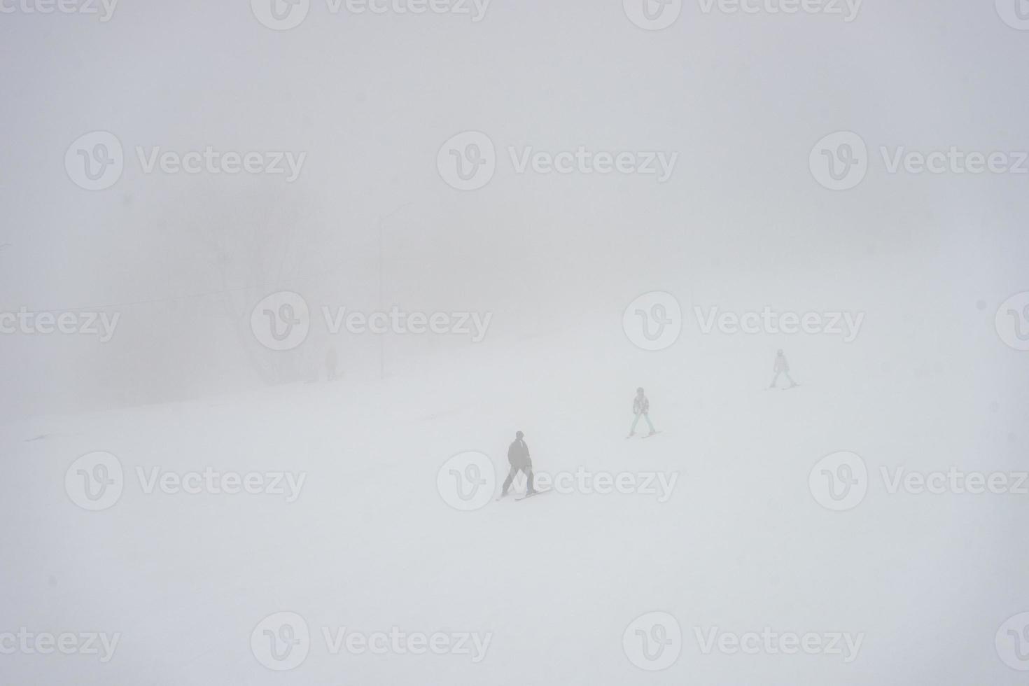 Skiers on the slopes in misty day photo