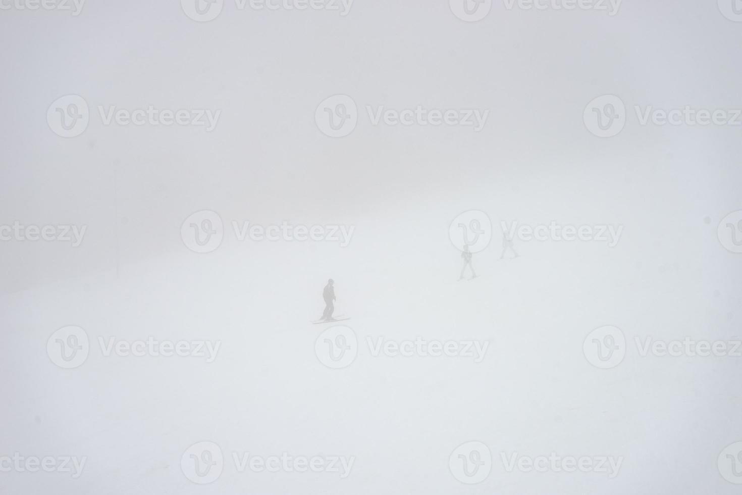 Skiers on the slopes in misty day photo