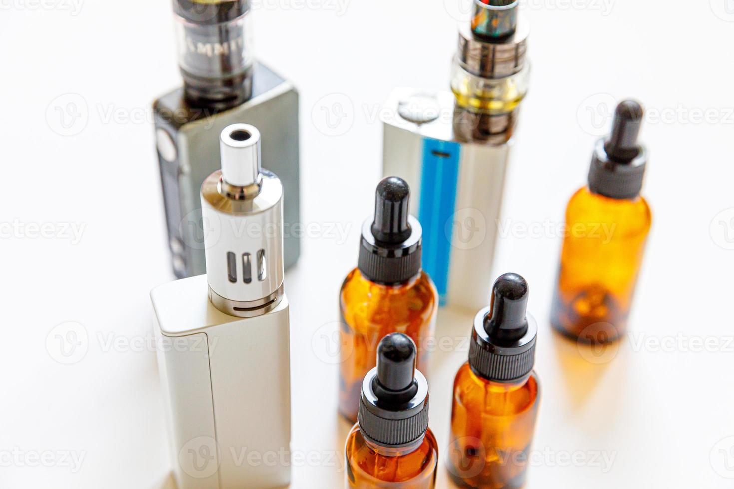 Vaping device e-cigarette electronic cigarette and liquid bottles isolated on white background. Vape device for alternative smoking. Vaping shop concept. Gadget for vaper. Vaping accessories. photo