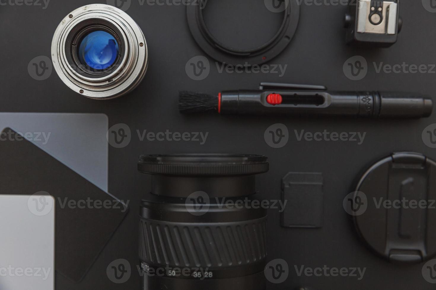 Photographer workplace with dslr camera system, camera cleaning kit, lens and camera accessory on dark black table background. Hobby travel photography concept Flat lay top view copy space photo