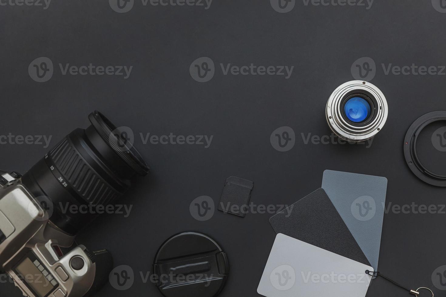 Photographer workplace with dslr camera system, camera cleaning kit, lens and camera accessory on dark black table background. Hobby travel photography concept Flat lay top view copy space photo