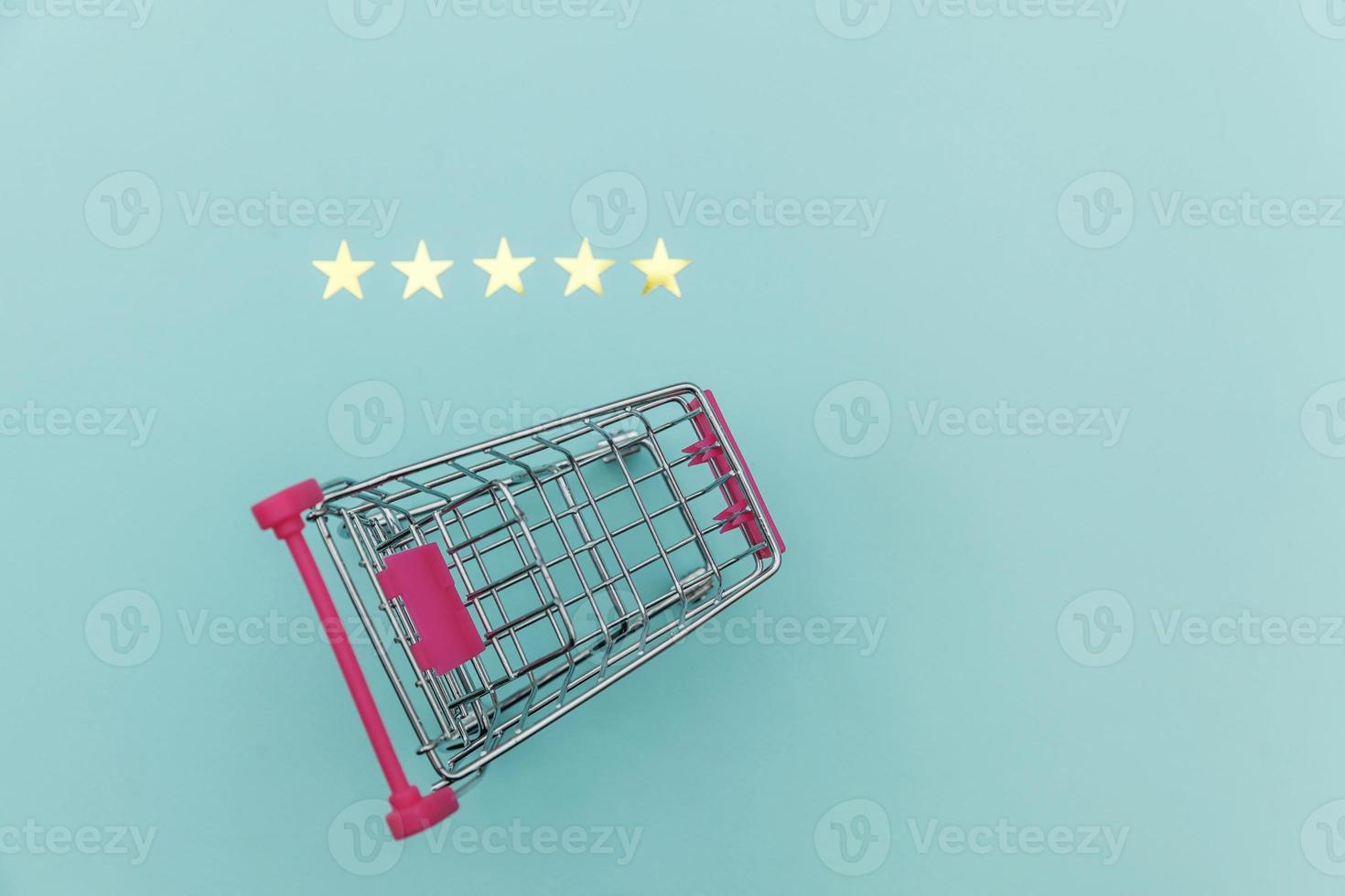 Small supermarket grocery push cart for shopping toy with wheels and 5 stars rating isolated on pastel blue background. Retail consumer buying online assessment and review concept. photo