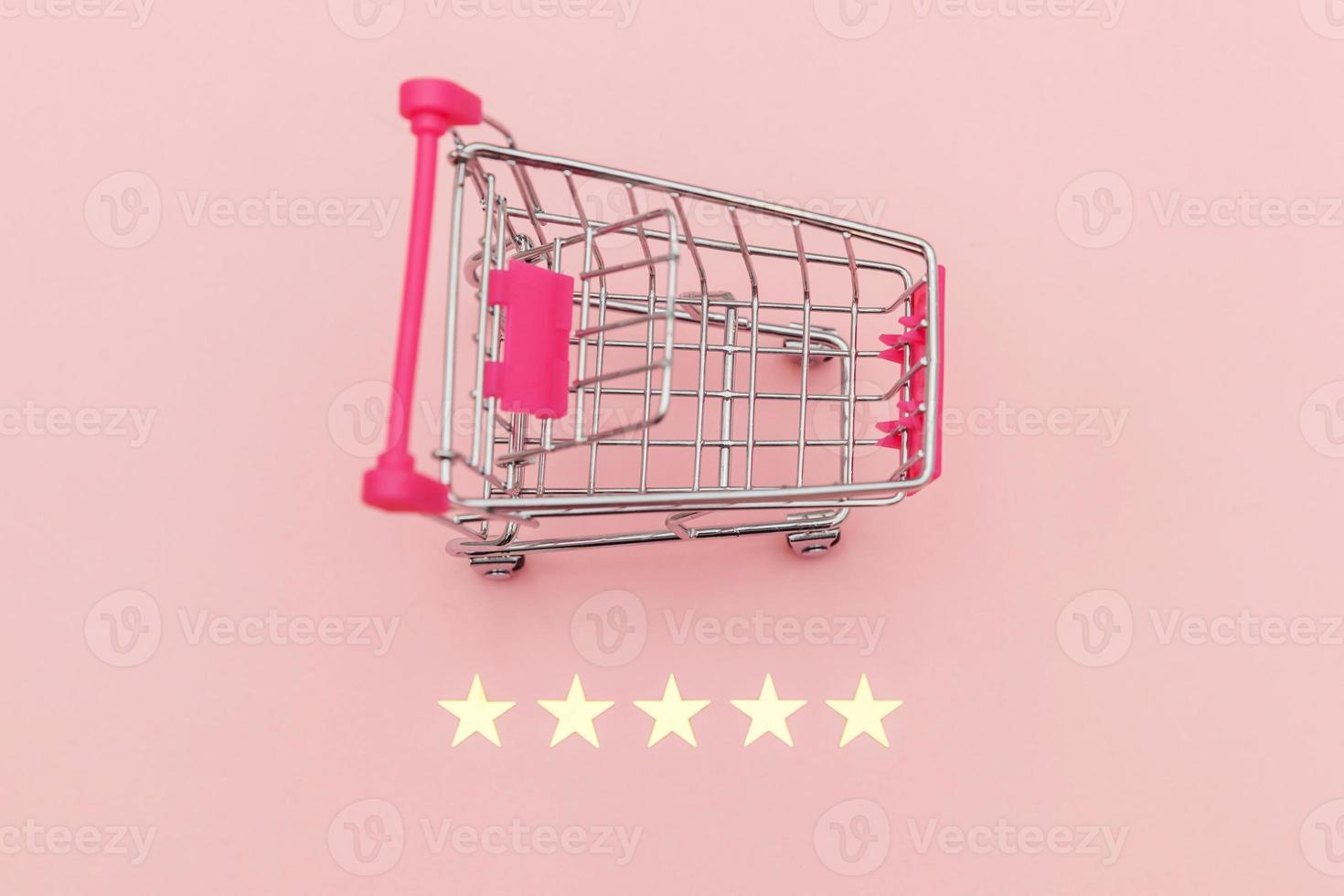 Small supermarket grocery push cart for shopping toy with wheels and 5 stars rating isolated on pastel pink background. Retail consumer buying online assessment and review concept. photo