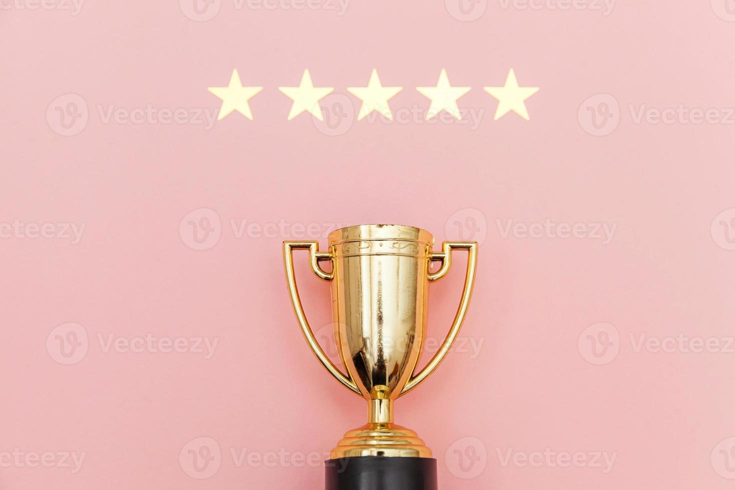 Simply flat lay design winner or champion gold trophy cup and 5 stars rating isolated on pink pastel background. Victory first place of competition. Winning or success concept. Top view copy space. photo