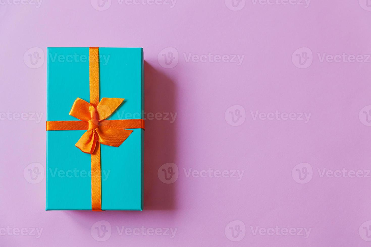 Christmas New Year birthday valentine celebration present romantic concept. Simply minimal design blue gift box isolated on violet purple colorful background. Flat lay top view, copy space photo