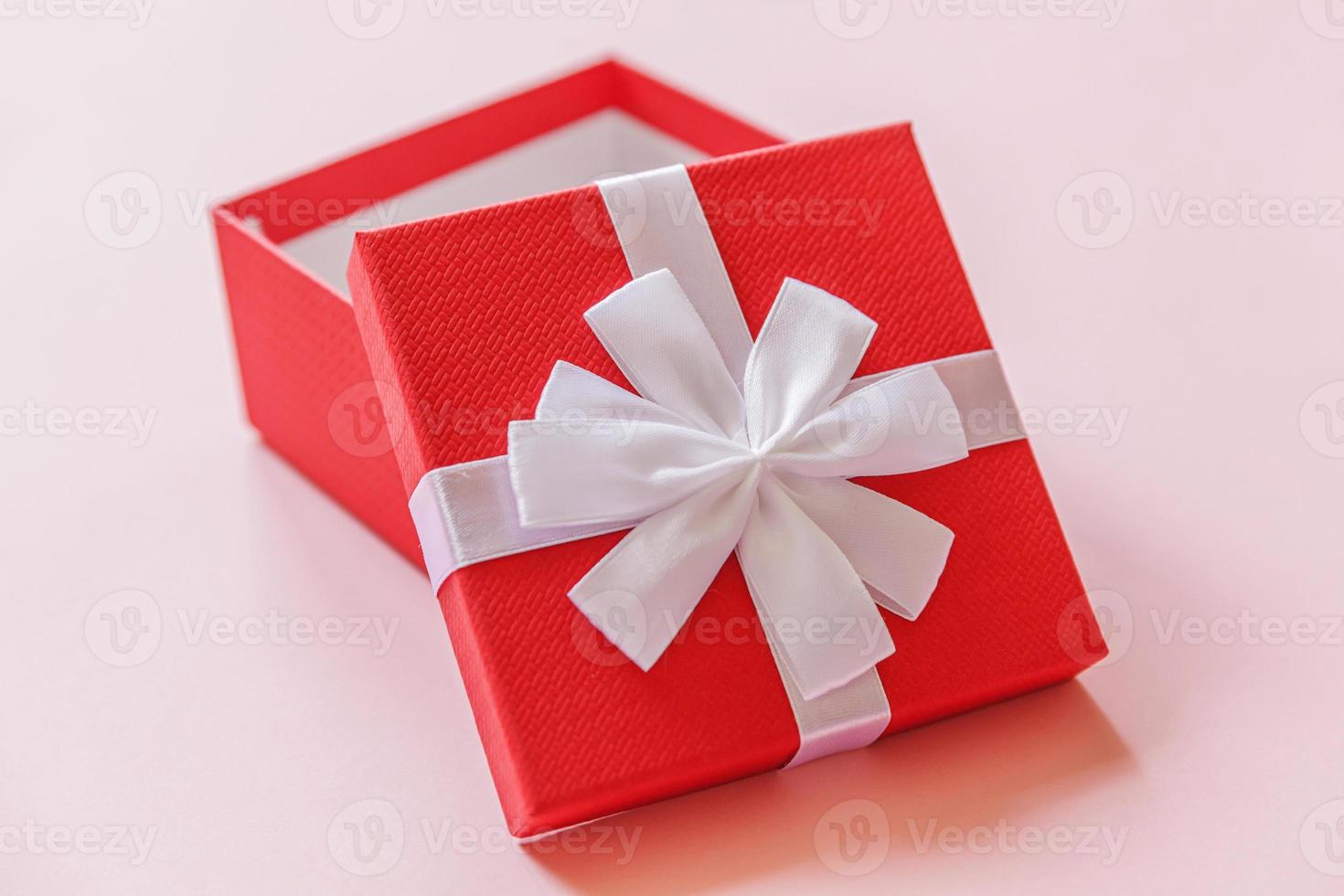 Christmas New Year birthday valentine celebration present romantic concept. Simply minimal design red gift box isolated on pastel pink colorful background. Flat lay top view, copy space photo