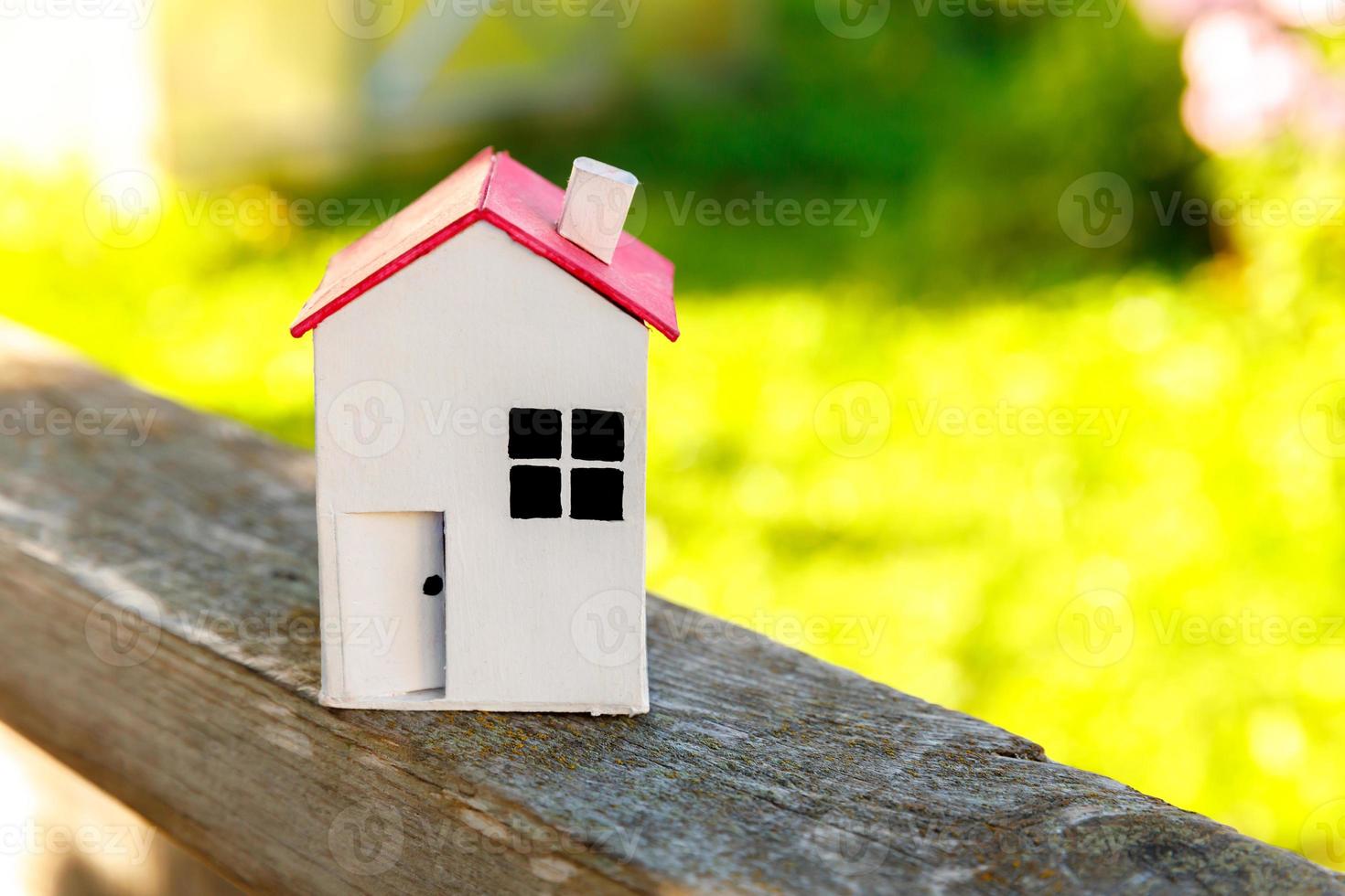 casa modelo de juguete blanco en miniatura con fondo de madera cerca de fondo verde. aldea ecológica, fondo ambiental abstracto. concepto de ecología de casa de ensueño de seguro de propiedad de hipoteca de bienes raíces. foto