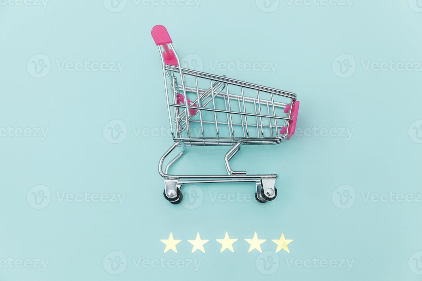 carrito de supermercado pequeño para comprar juguetes con ruedas y calificación de 5 estrellas aislado en fondo azul pastel. concepto de evaluación y revisión en línea de compra de consumidores minoristas. foto