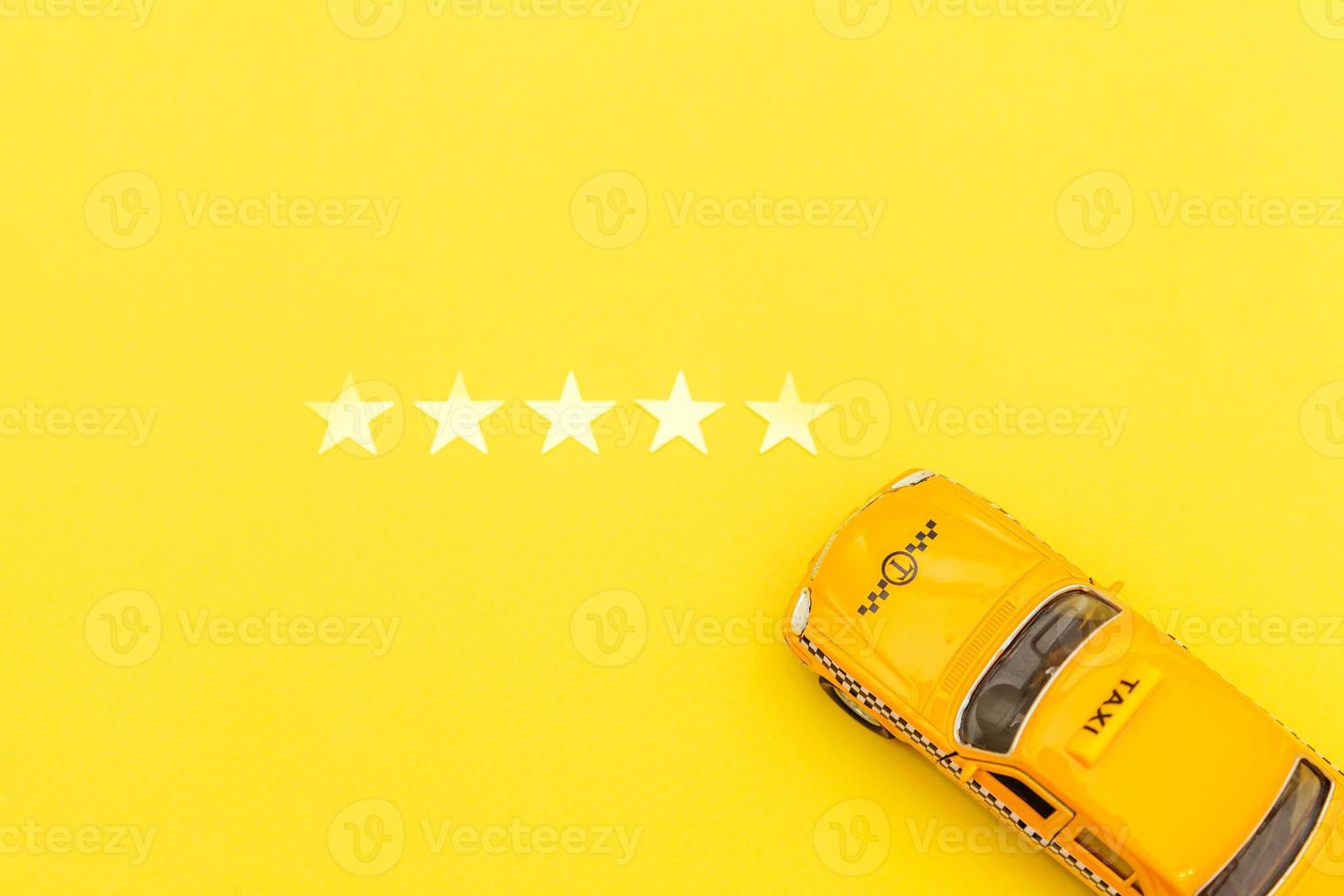 taxi de coche de juguete amarillo y calificación de 5 estrellas aislado sobre fondo amarillo. aplicación de teléfono inteligente del servicio de taxi para buscar en línea llamadas y reservar el concepto de taxi. símbolo de taxi. copie el espacio foto