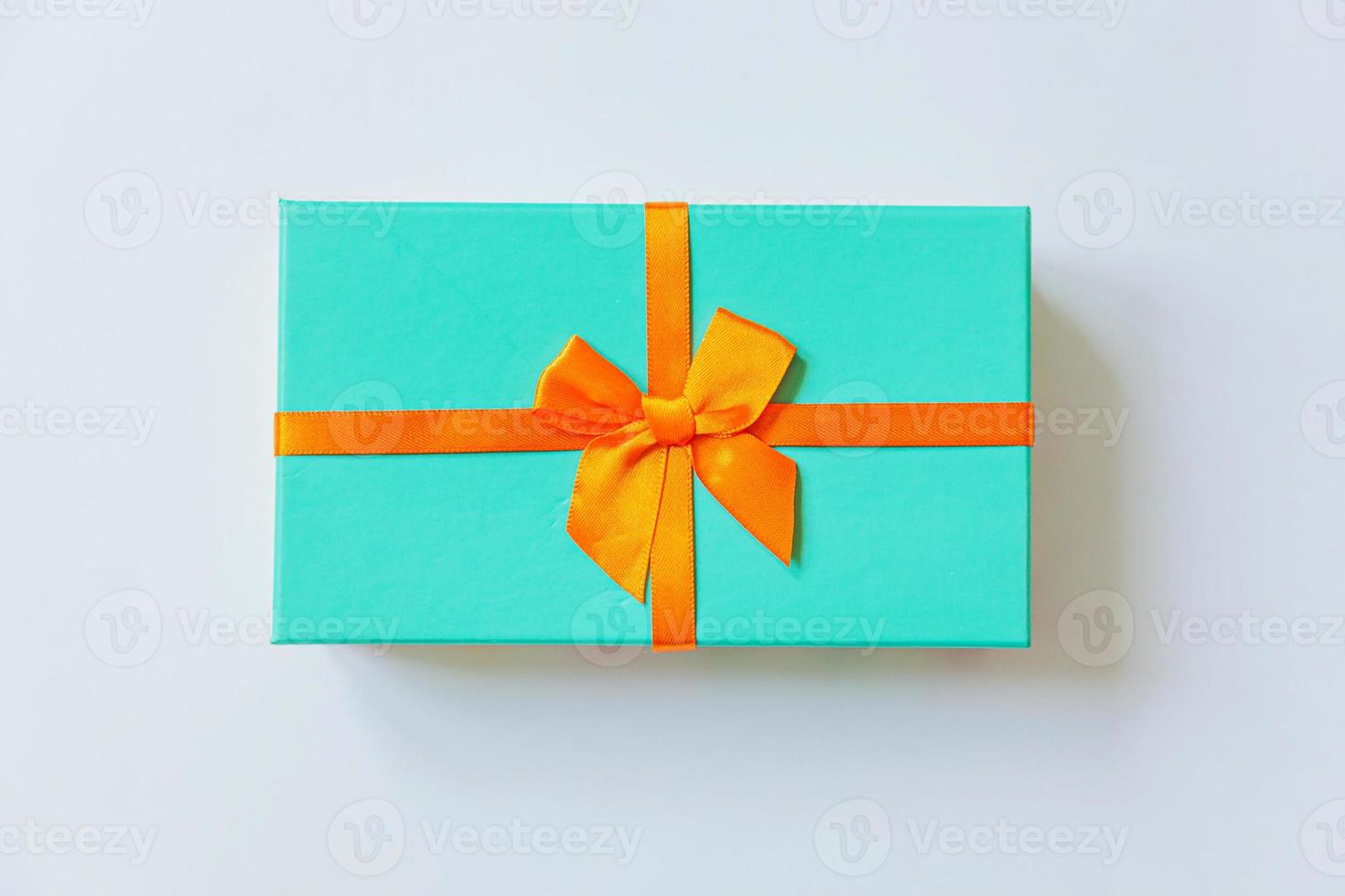 Christmas New Year birthday valentine celebration present romantic concept. Simply minimal design blue gift box with orange ribbon isolated on white background. Flat lay top view copy space. photo