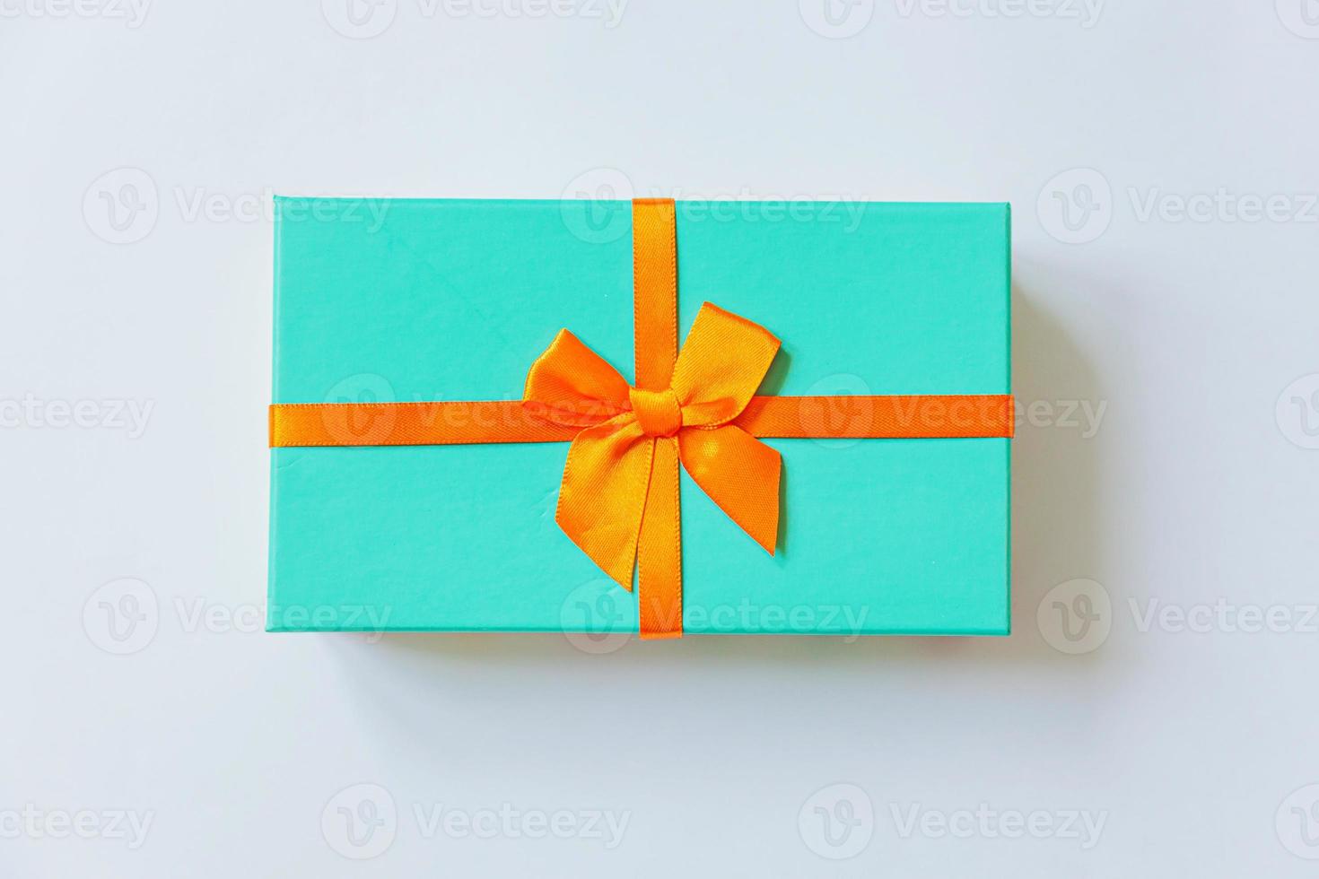 navidad año nuevo cumpleaños san valentín celebración presente concepto romántico. caja de regalo azul de diseño minimalista con cinta naranja aislada en fondo blanco. espacio de copia de vista superior plana. foto