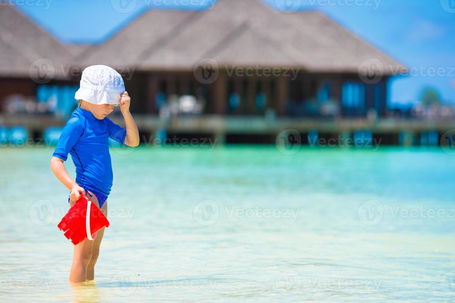 adorable niña jugando con juguetes de playa durante las vacaciones tropicales foto