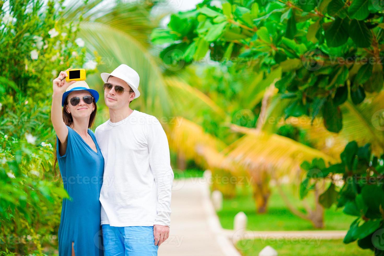 Young happy couple making selfie with mobile phone on tropical vacation photo