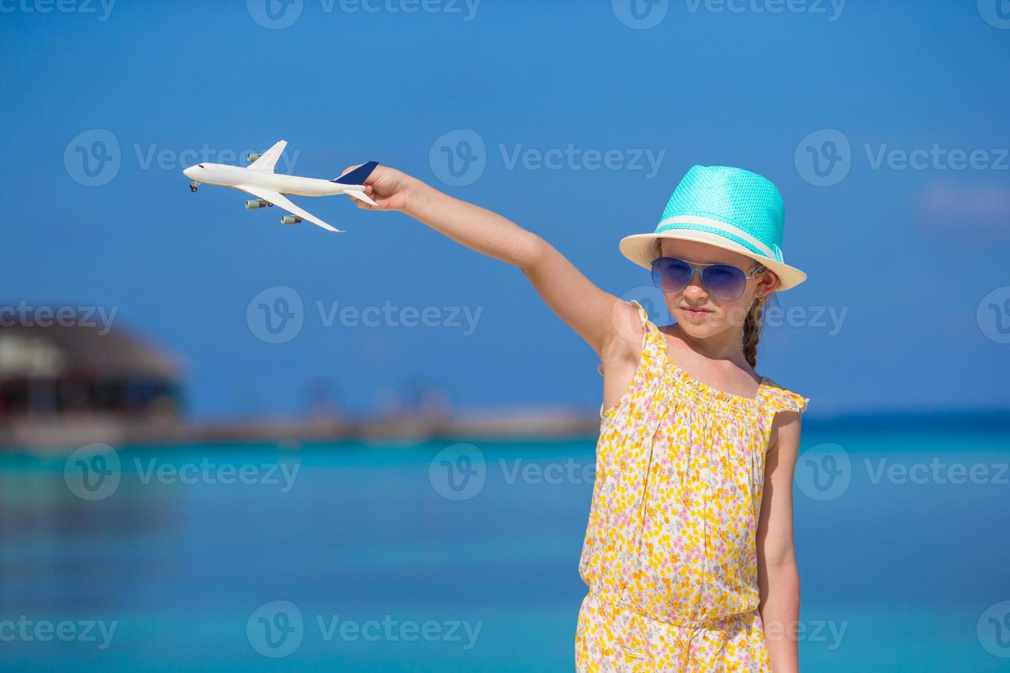 niña feliz con avión de juguete en las manos en la playa de arena blanca foto