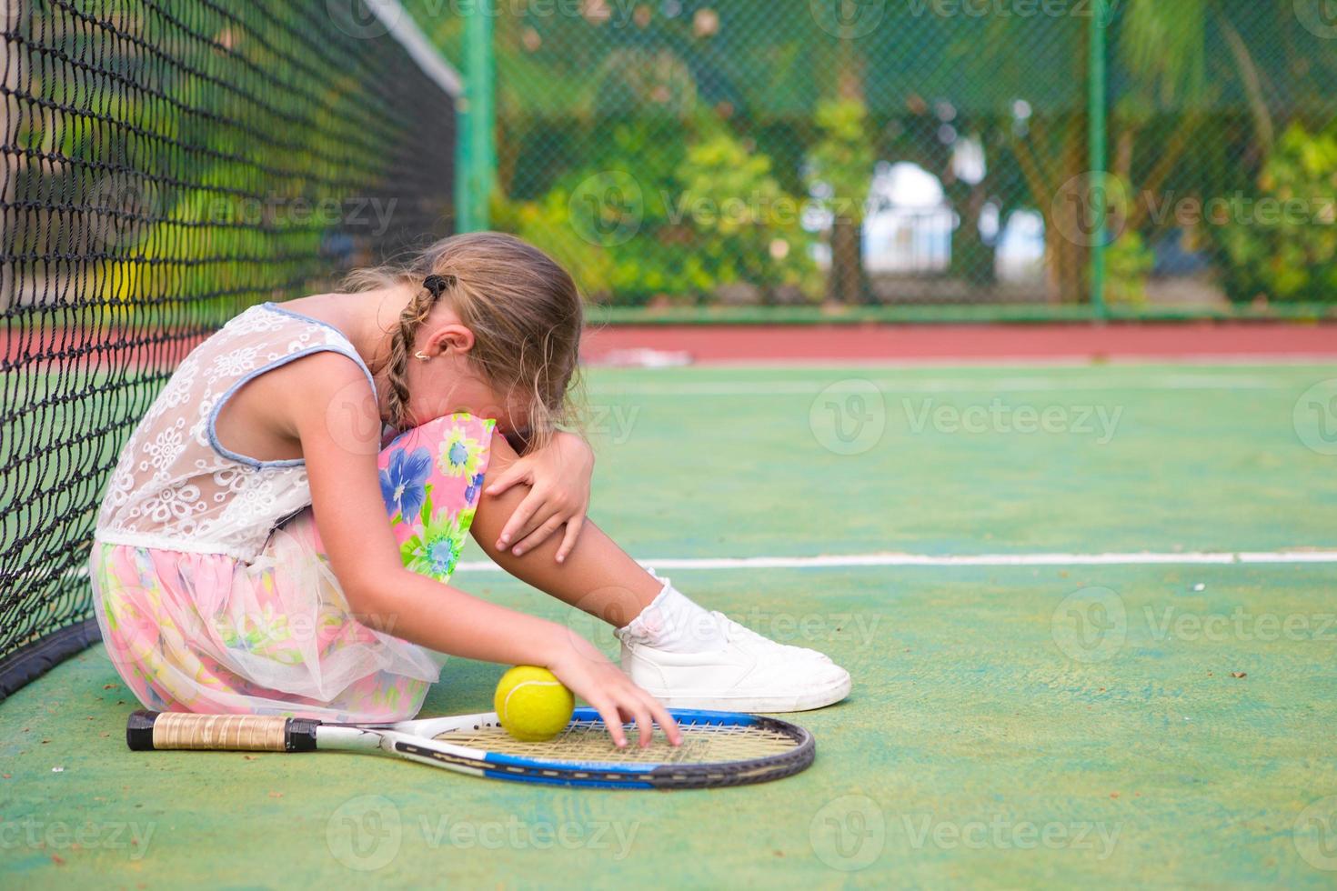 Little sad girl on tennis court photo