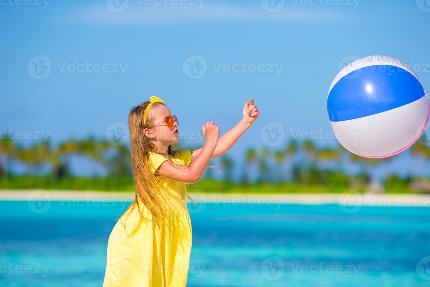 Little adorable girl playing on beach with ball photo