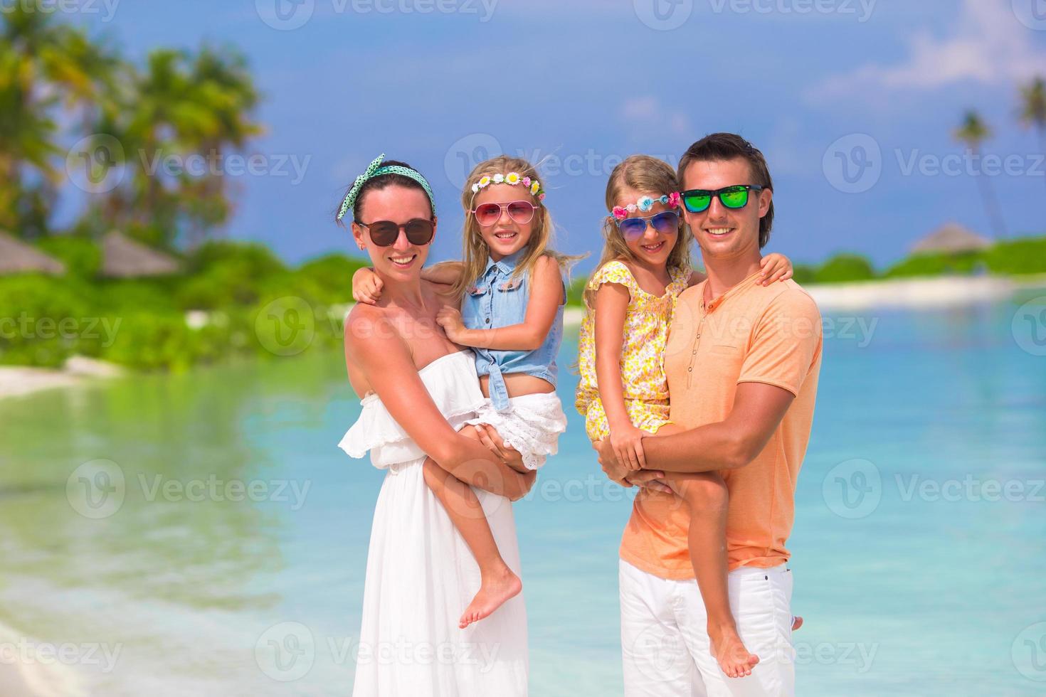 joven familia de cuatro en vacaciones en la playa foto
