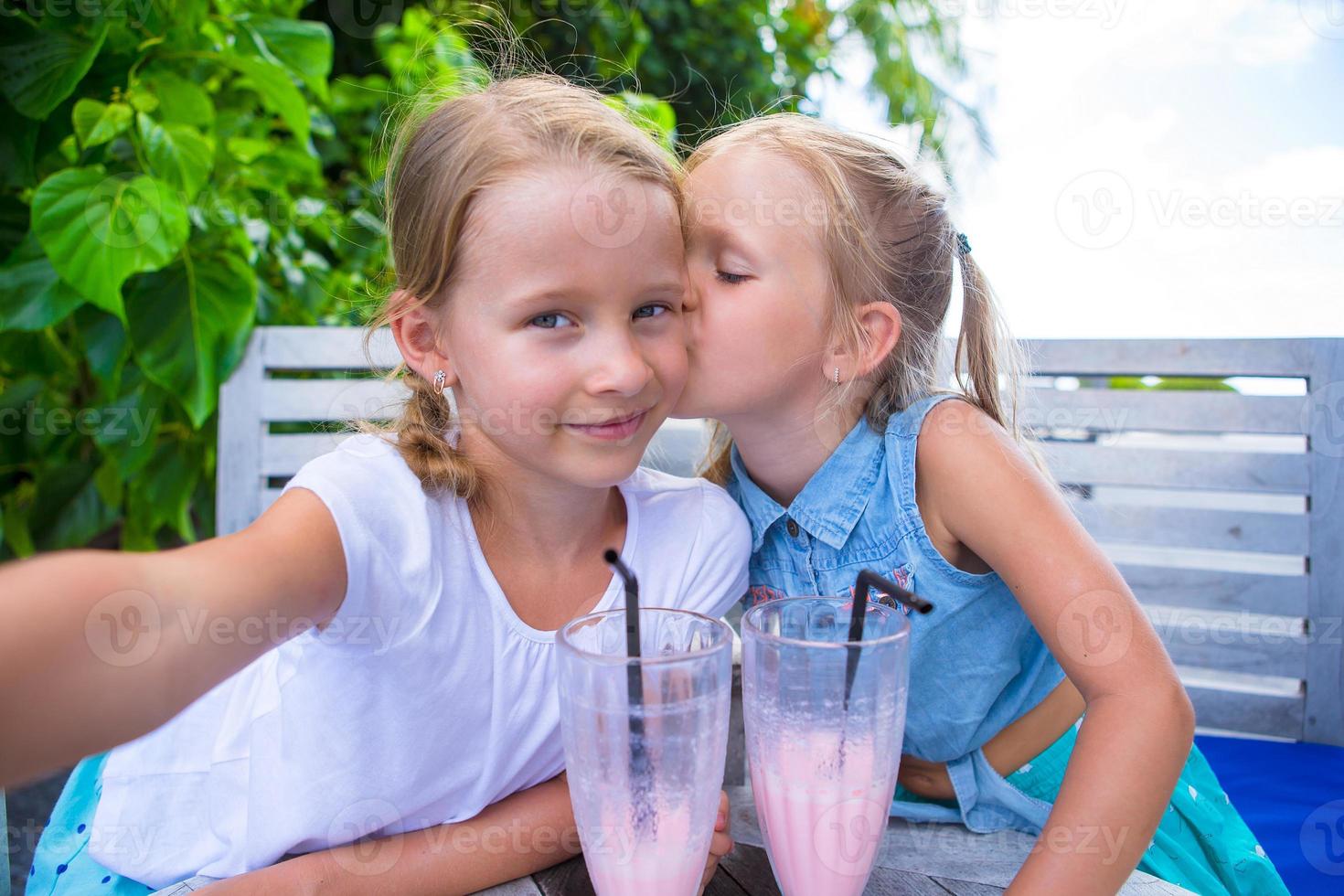 niñas pequeñas tomando selfie y bebiendo sabrosos cócteles en un resort tropical foto
