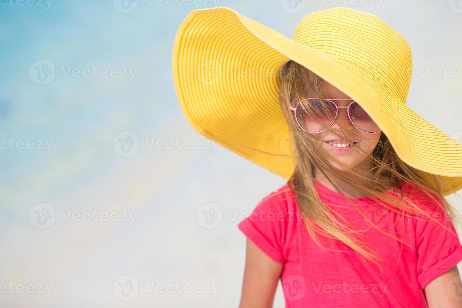 Adorable little girl in hat at beach during summer vacation photo