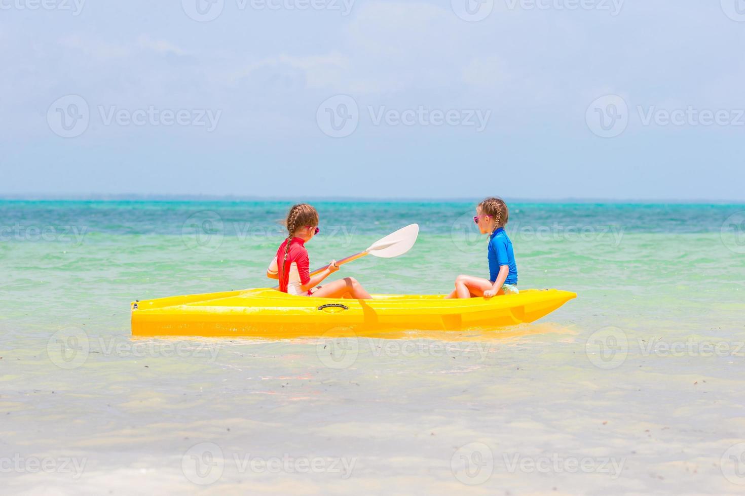 Little adorable girls enjoying kayaking on yellow kayak photo