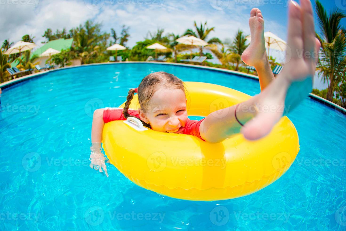 retrato de niño feliz con círculo de goma inflable divirtiéndose en la piscina foto