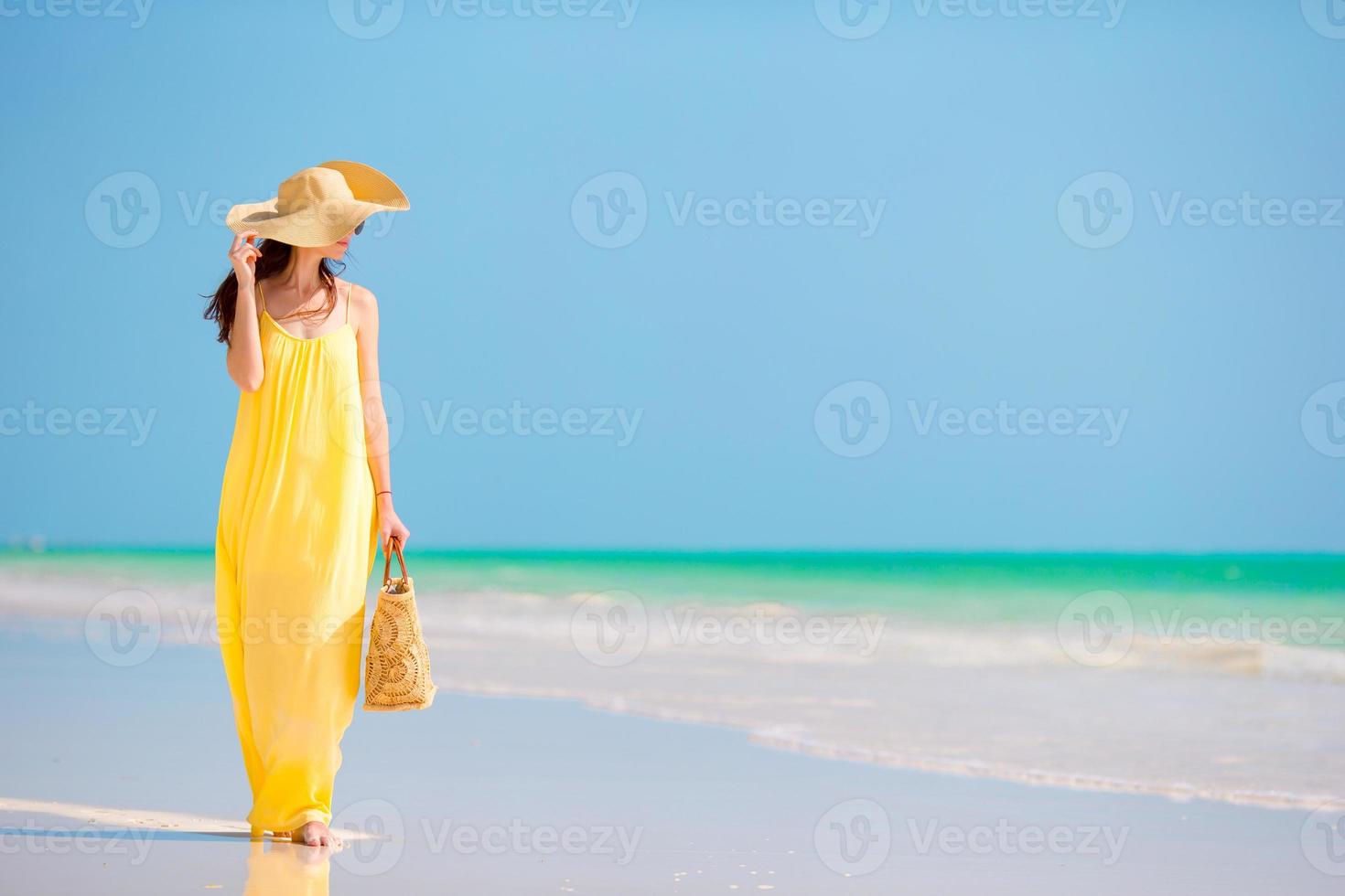 Young beautiful woman in big hat during tropical beach vacation photo