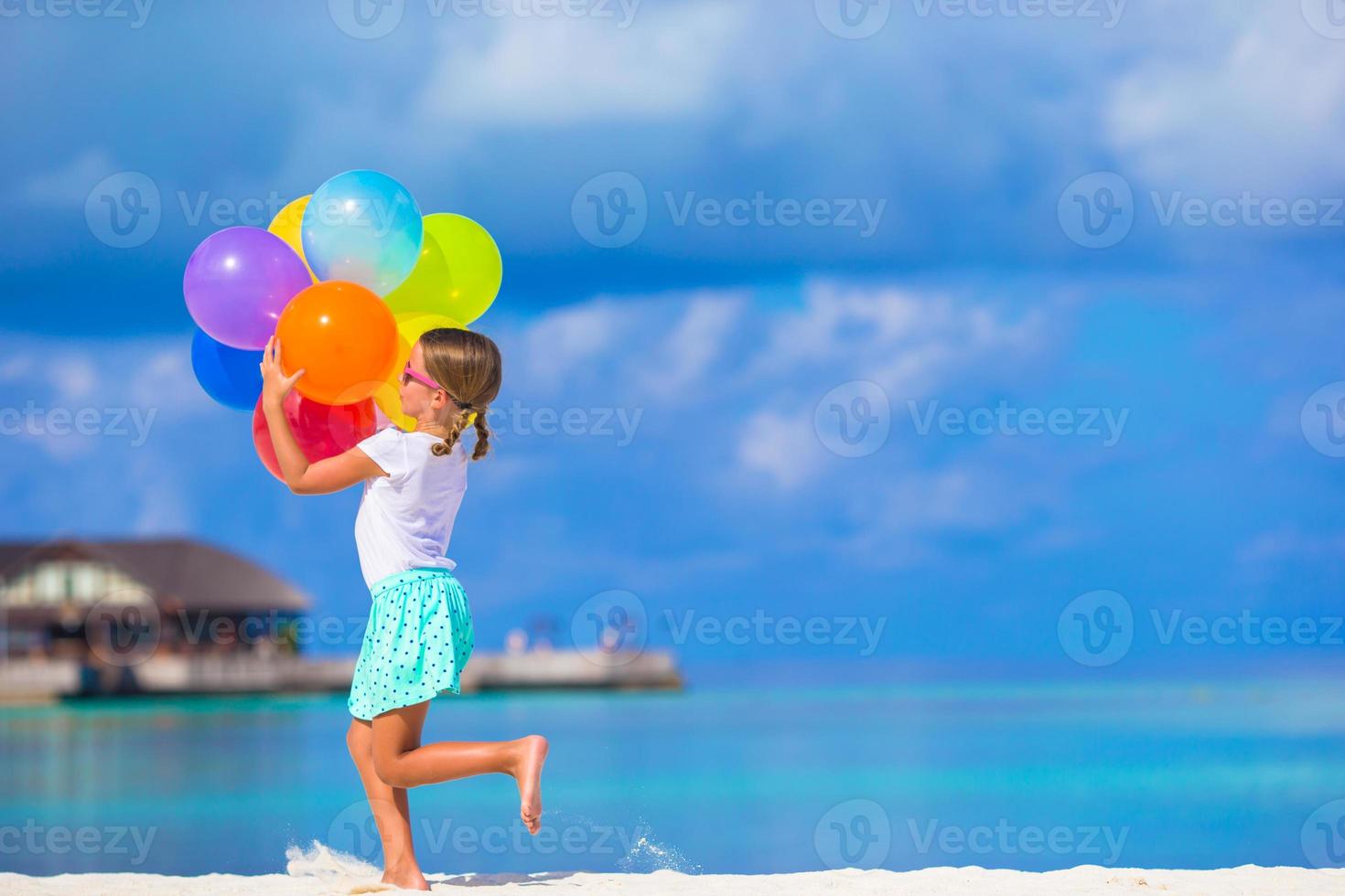 Cute little girl playing with balloons at the beach photo