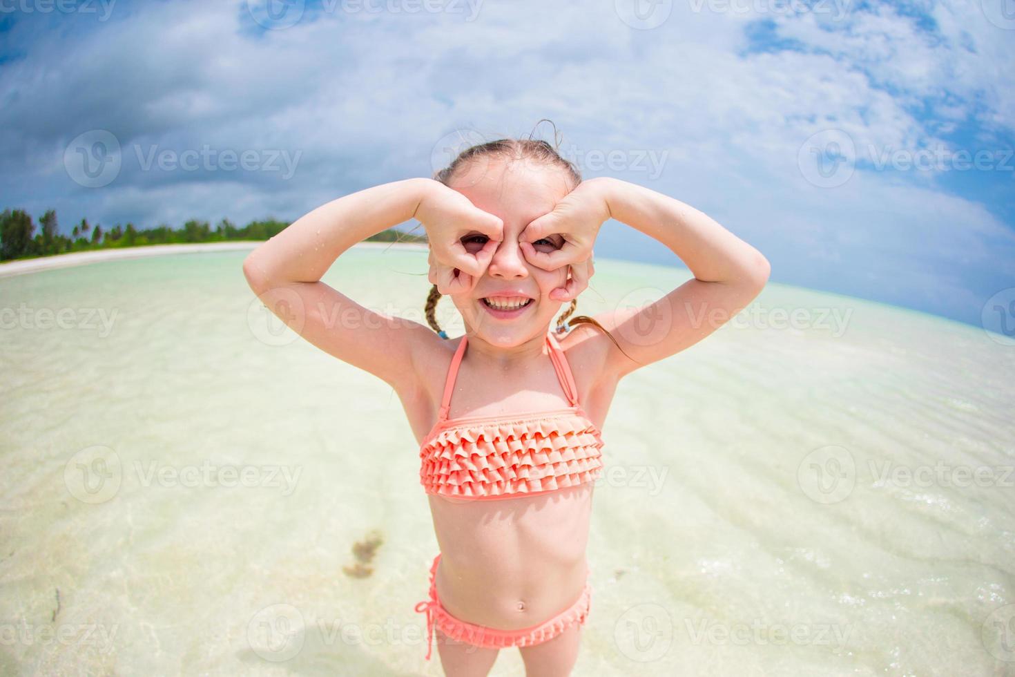 Adorable little girl having fun like as a superhero at beach during summer vacation photo