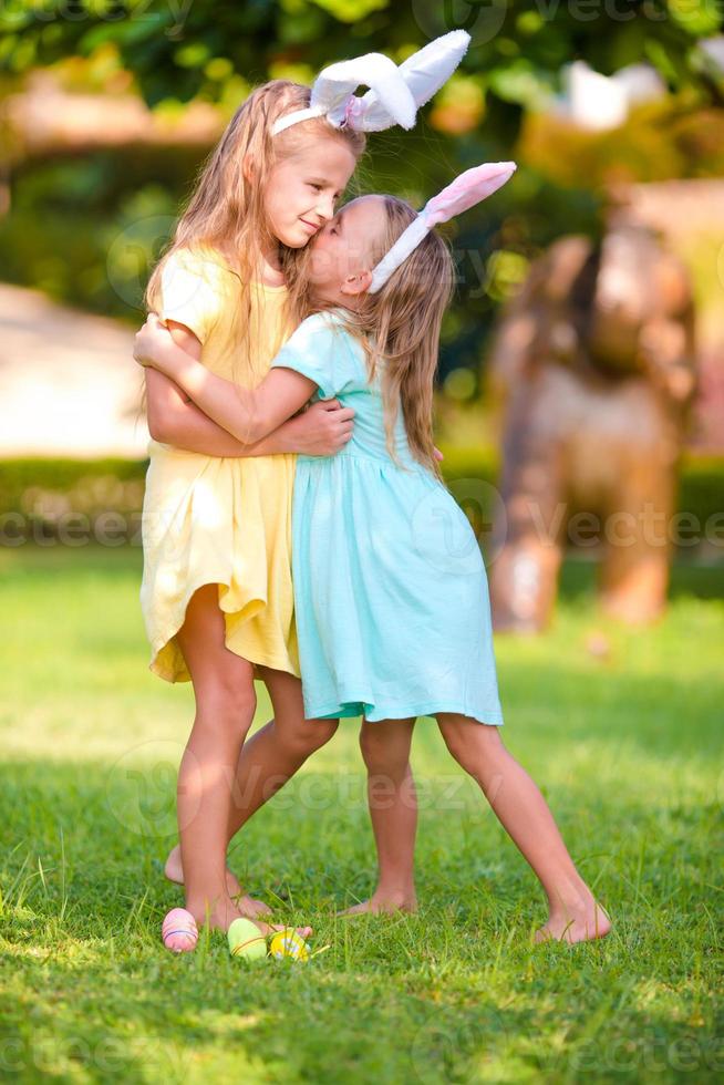 dos adorables hermanitas con orejas de conejo el día de pascua al aire libre foto