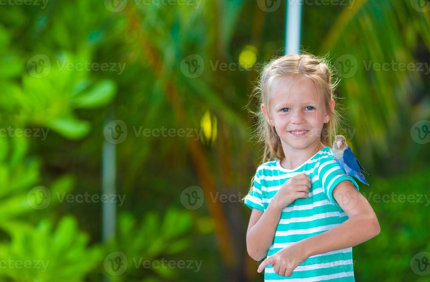 adorable niña feliz en la playa con colorido pajarito foto