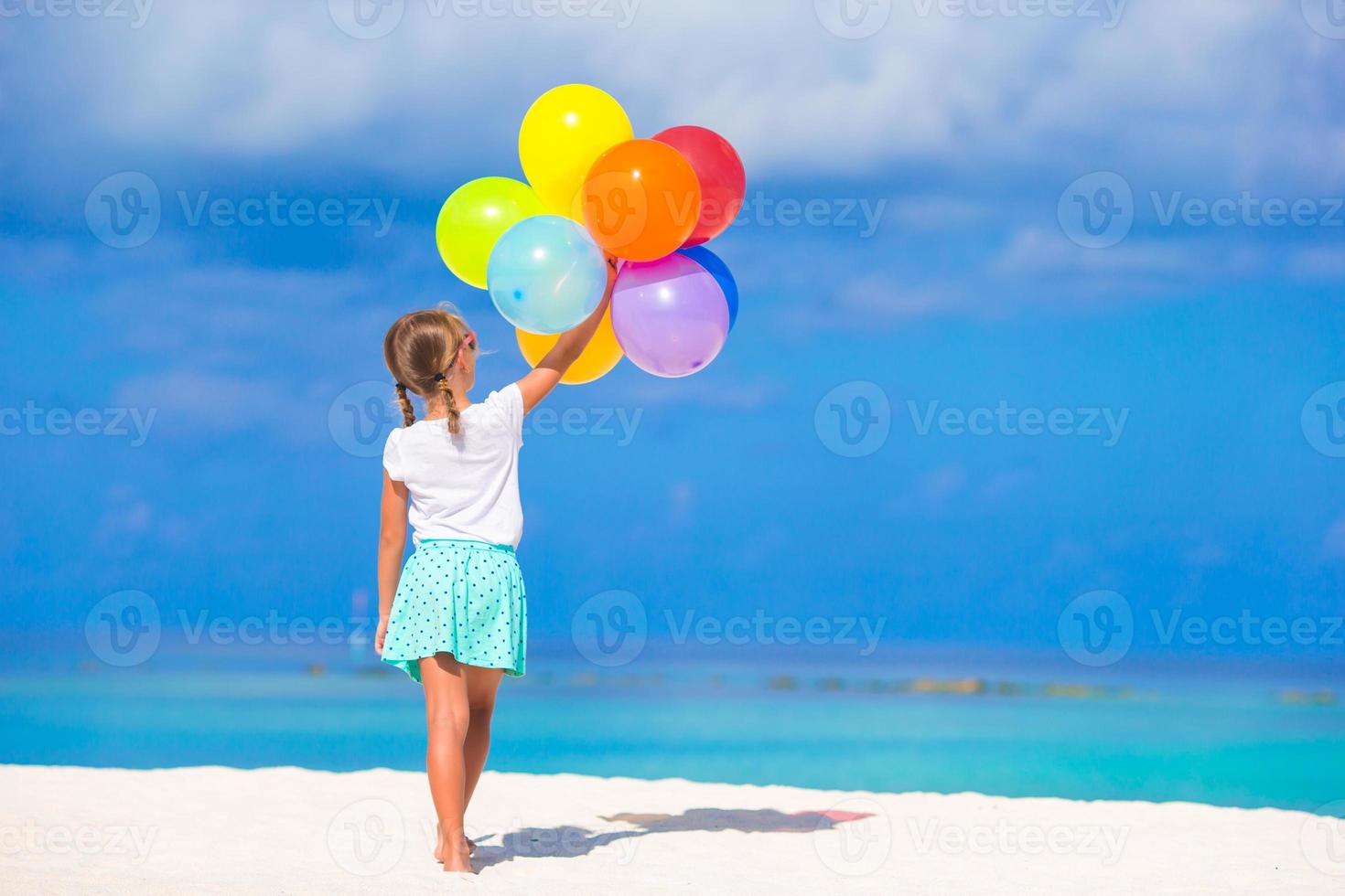 Adorable little girl playing with balloons at the beach photo