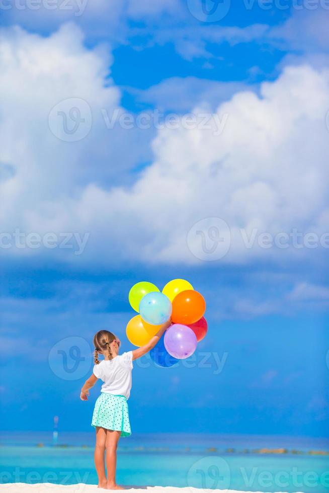 Adorable little girl playing with balloons at the beach photo