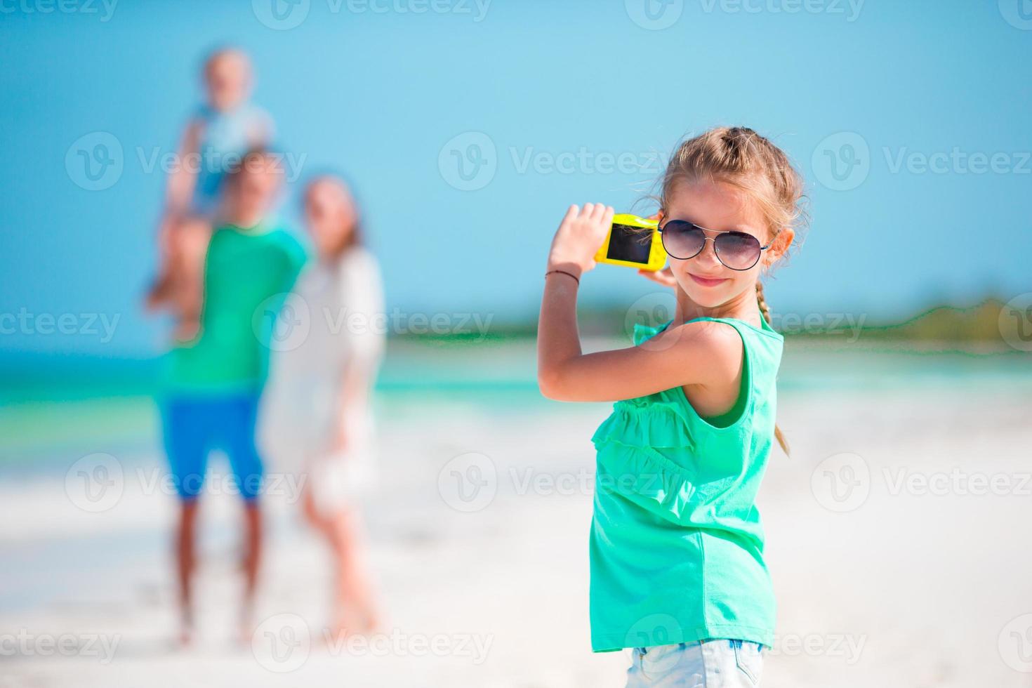 Little girl making photo on phone of family at the beach