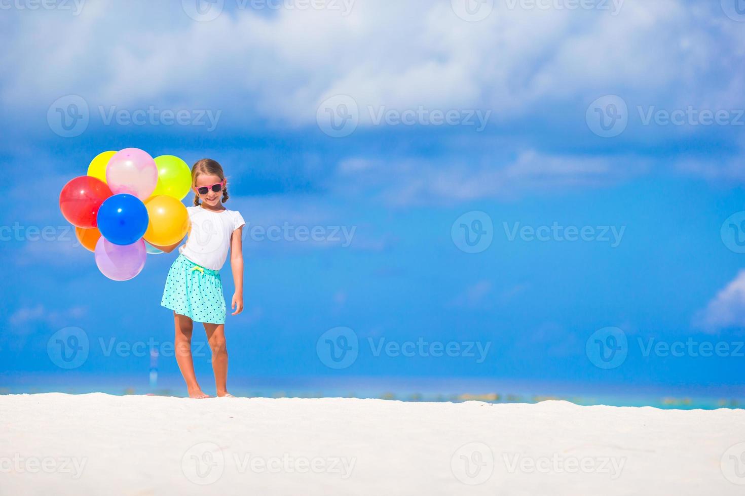 Adorable little girl playing with balloons at the beach photo