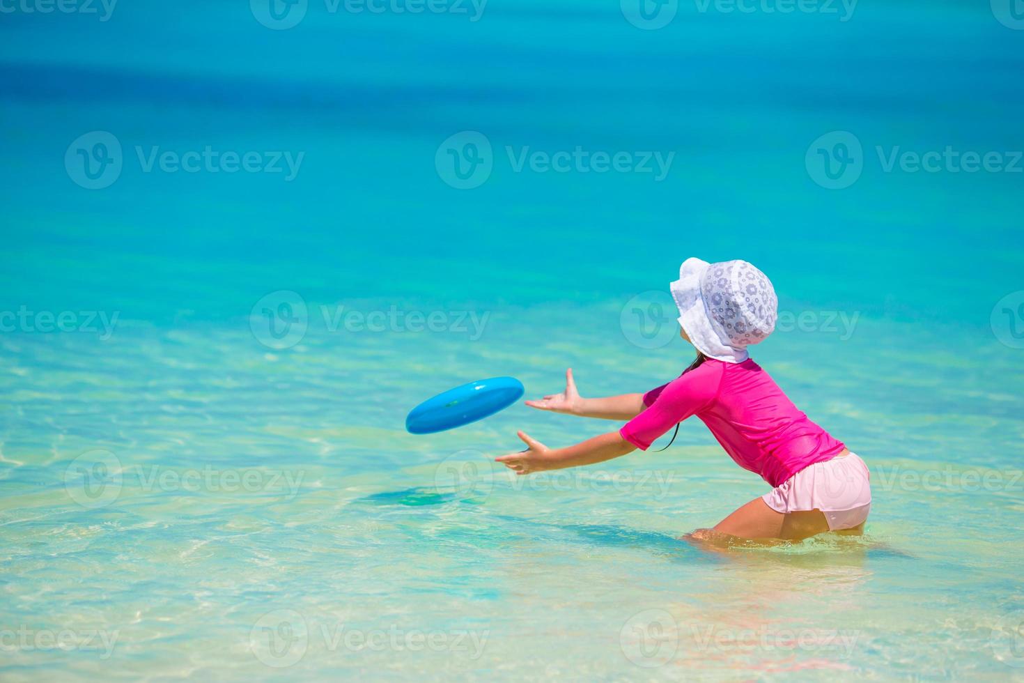 Niña jugando con disco volador en la playa de wnite foto