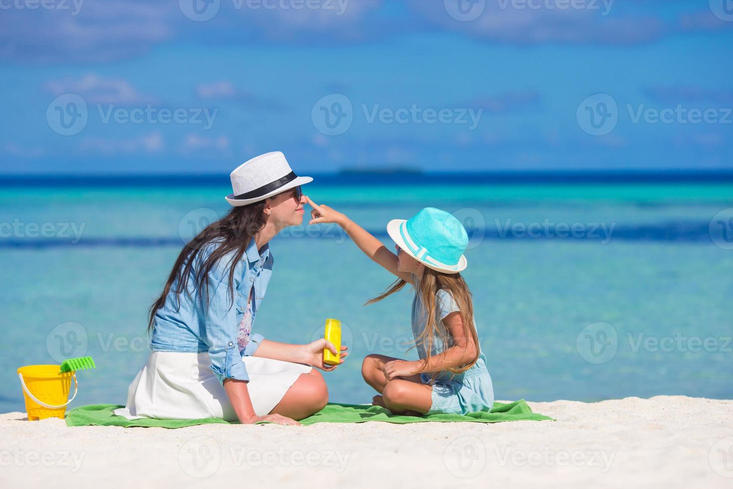 niña aplicando crema solar en la nariz de su madre foto