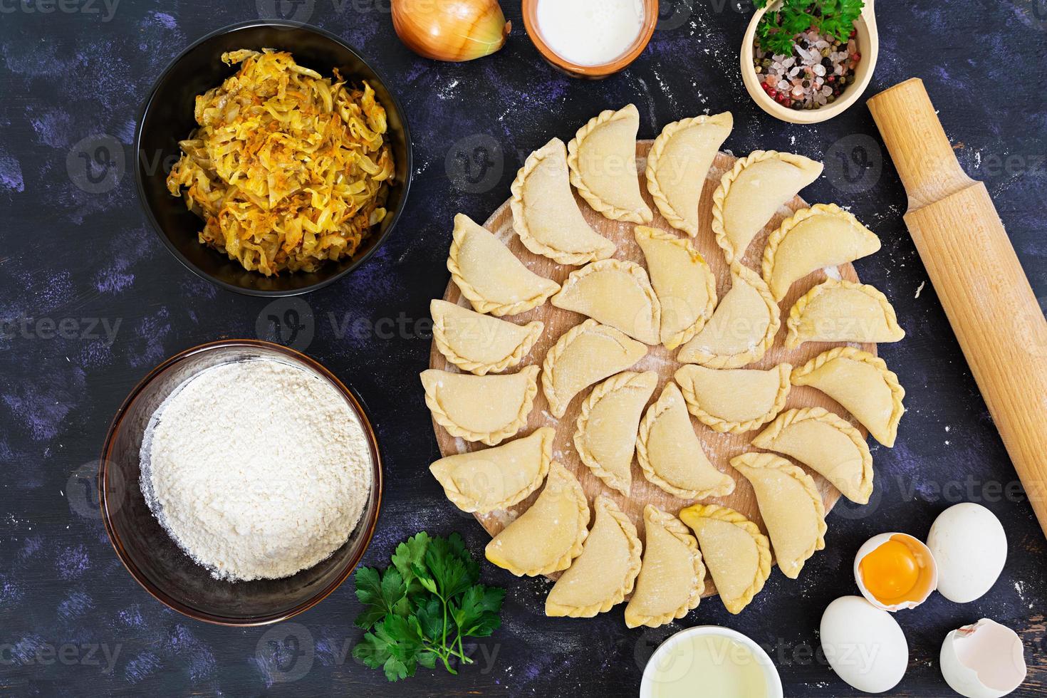 Delicious dumplings with cabbage on dark background. Top view photo