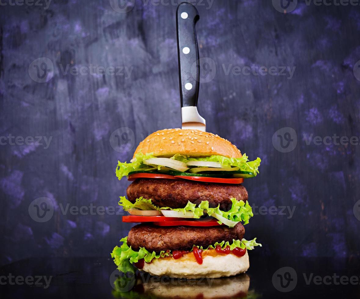 deliciosa hamburguesa hecha a mano sobre fondo oscuro. vista cercana foto