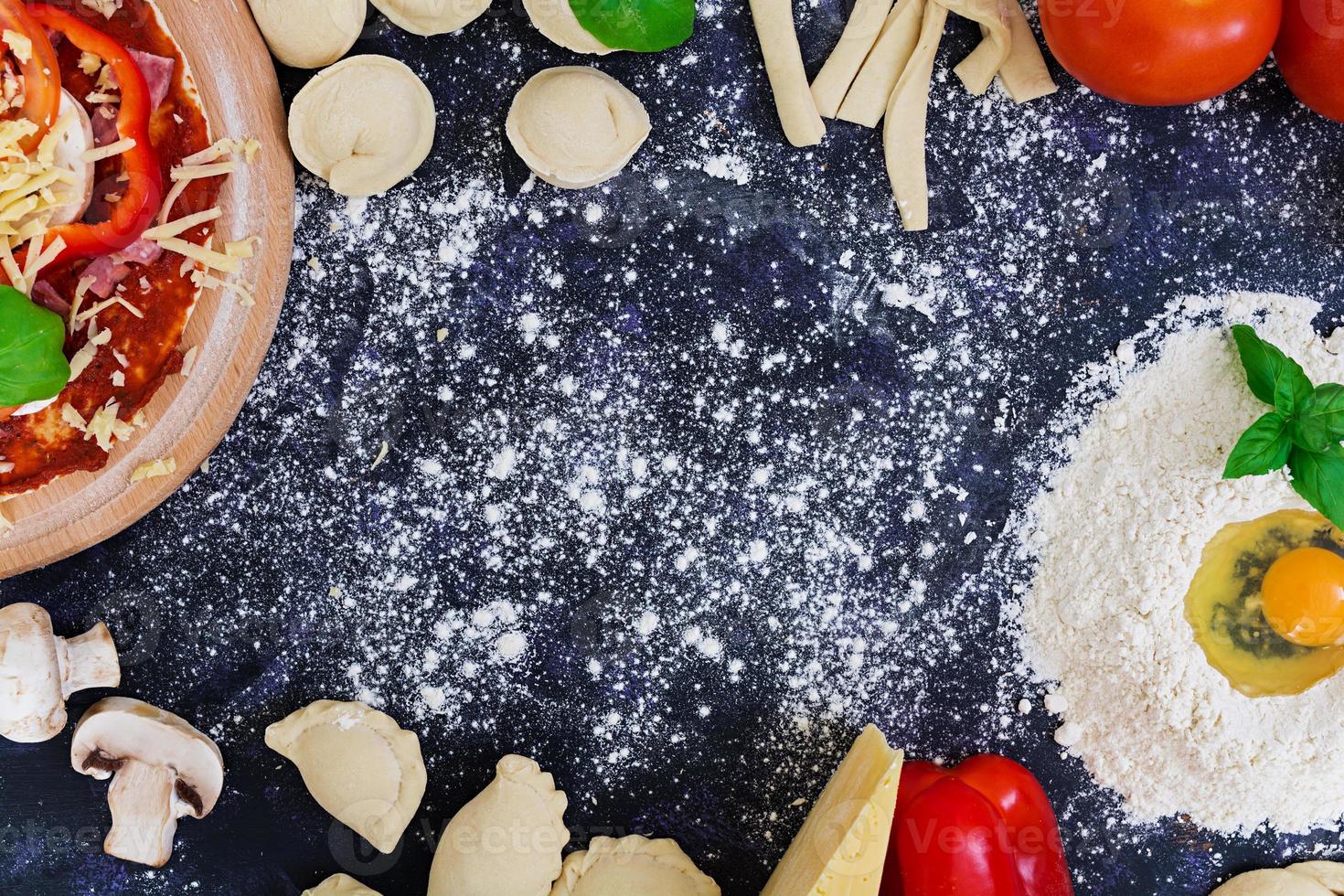 Raw pizza dough with ingredients and spices on dark background. Top view photo