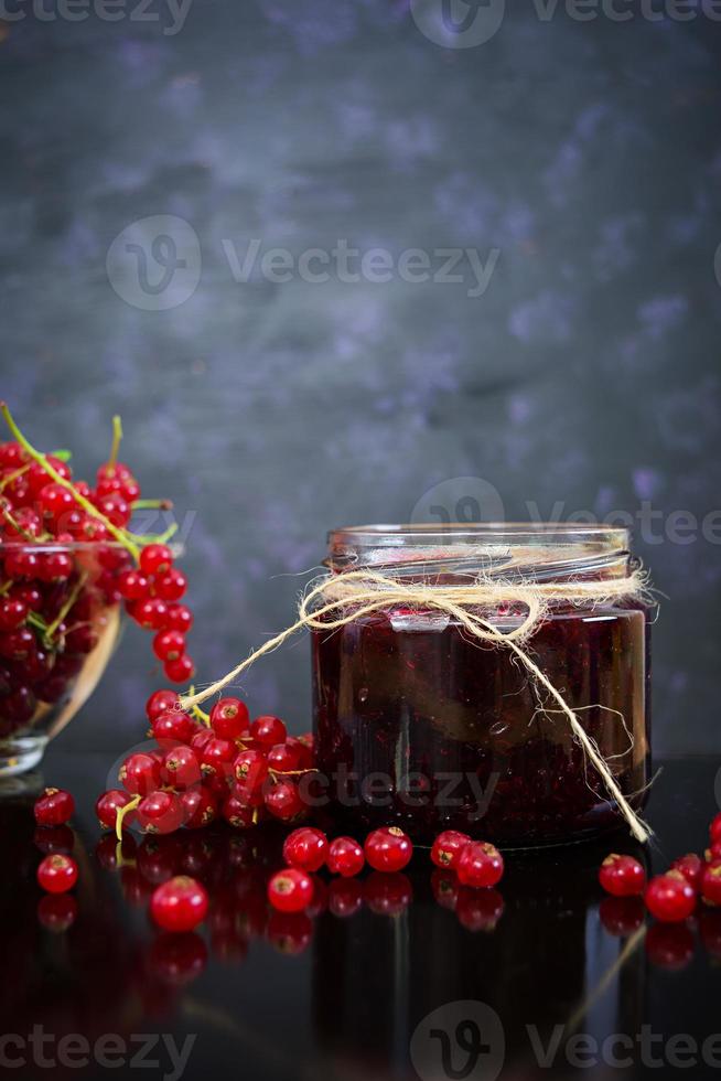 Jar with jam of red currant on dark background photo